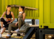 Two women chatting outside the shipping container gym post workout.